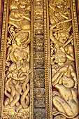 Wat Xieng Thong temple in Luang Prabang, Laos. Detail of a wooden door of the sim with gilded carvings on a red background. 